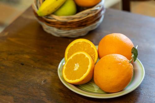 a plate of oranges on a table with a basket of fruit at Sognare nel Castello in Monteriggioni