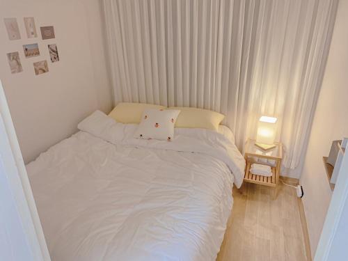a small bedroom with a white bed and a lamp at Easel House in Seoul