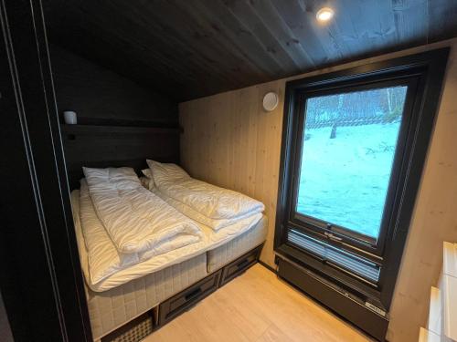 a small bed in a room with a window at Gudbrandsdalen view cabin in Strande