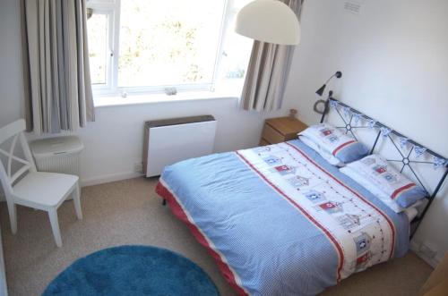 een slaapkamer met een bed, een stoel en een raam bij Lovely cottage in Snowdonia, private hot tub, by mountains & award winning beach in Fairbourne