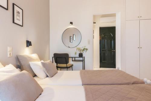 a white bedroom with a bed and a chair at Ciel Comfort Living in Laganas