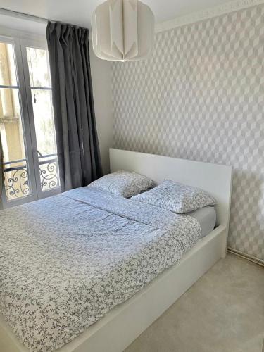 a bedroom with a white bed with a window and a bed sqor at Neuilly's Finest in Neuilly-sur-Seine