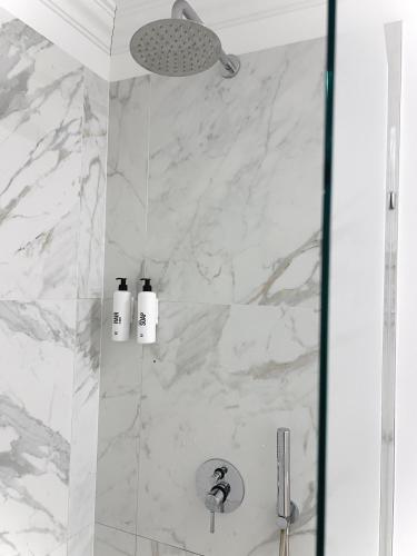 a shower with white marble walls and two bottles of soap at Tomy Old Town Apartments in Vilnius