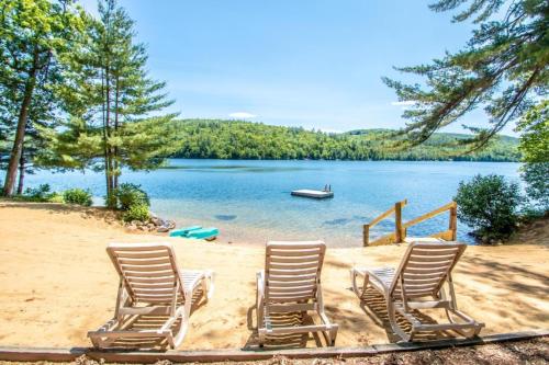 a group of chairs sitting on a beach next to a lake at Squam Lake 3 bed plus 3 bath rental (Suite 7) in Holderness