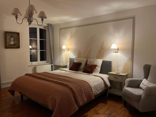 1 dormitorio con 1 cama y 1 silla en Le Clos du Bas Courtil Guesthouse Omaha Beach, en Osmanville
