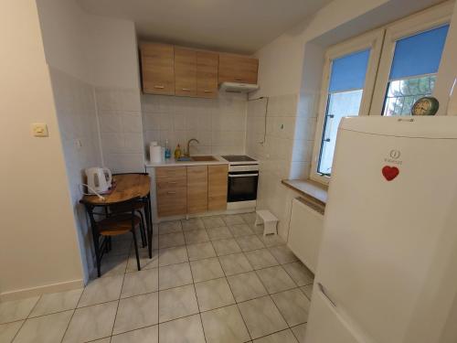 a kitchen with a table and a white refrigerator at Emilka 2 in Suwałki