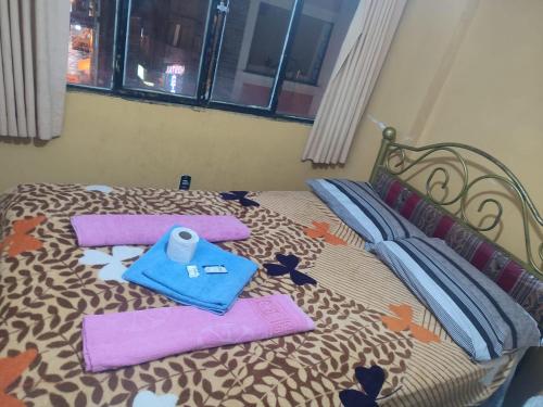 a bed with purple towels and a blue bag on it at Hostal Arco Iris in Copacabana