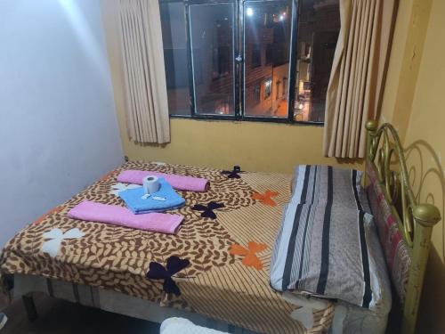 a small bedroom with a bed with a blanket and pillows at Hostal Arco Iris in Copacabana