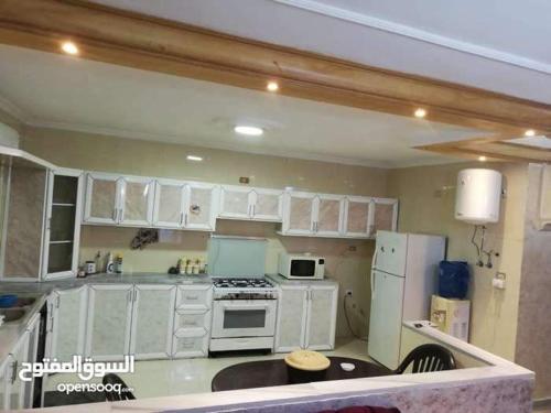 a kitchen with white cabinets and a stove top oven at شقة مفروشة سكنية في مرج الحمام in Amman
