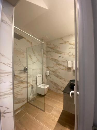 a bathroom with a toilet and a glass shower at Tirana Central Rooms in Tirana