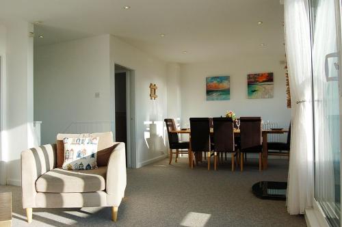 a living room with a chair and a dining room at Ann's Beach House in Tywyn in Tywyn
