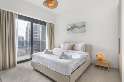 Downtown Dubai- 2BR Apartment in ACT Towers في دبي: غرفة نوم بيضاء مع سرير كبير ونافذة كبيرة