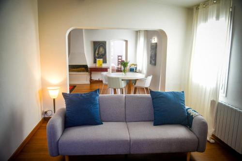 een woonkamer met een bank met blauwe kussens bij Rosella - Terrasse rooftop, hypercentre, wifi - by TGB in Ajaccio