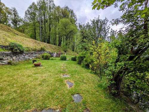 a garden with a stone wall and a grass field at Wild Valley Natura Pura in Valle Onsernone in Crana