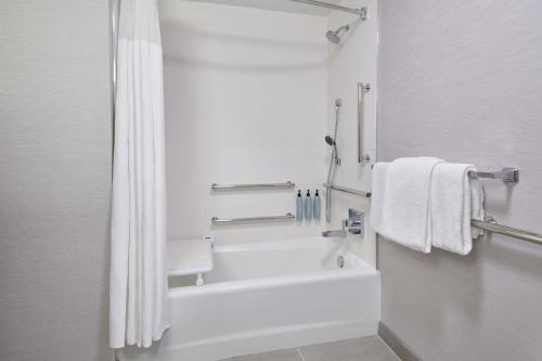 a bathroom with a tub and a shower with towels at Courtyard Detroit Metro Airport Romulus in Romulus