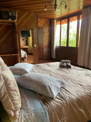 a bedroom with a large bed with two pillows at Casa Araucária 2 in Visconde De Maua