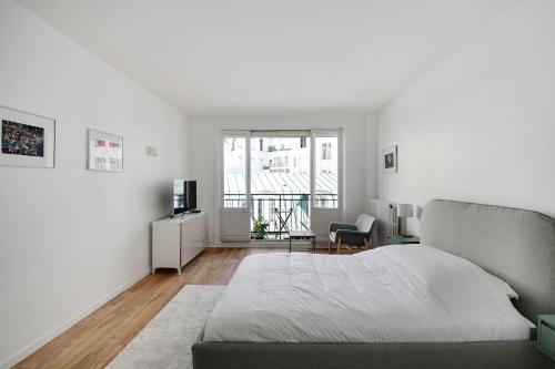 une chambre blanche avec un lit et une chaise dans l'établissement Bright Studio for 2 - Champs-Elysées, à Paris