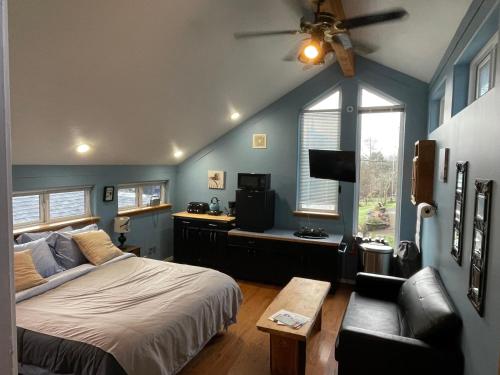 ein Schlafzimmer mit einem Bett, einem TV und einem Sofa in der Unterkunft Oceanfront Studio/Loft: Alpacas, Oysters & Kayaks in Shelton