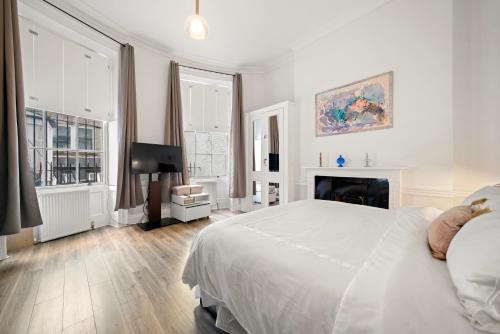 a white bedroom with a bed and a fireplace at Central London Rooms in London