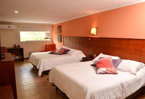2 Betten in einem Hotelzimmer mit orangefarbenen Wänden in der Unterkunft Hotel La Pedregosa in Mérida