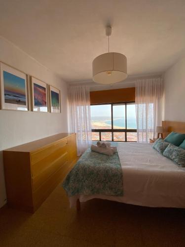 a bedroom with a large bed and a large window at NAZARÉ SURF APARTMENT in Nazaré