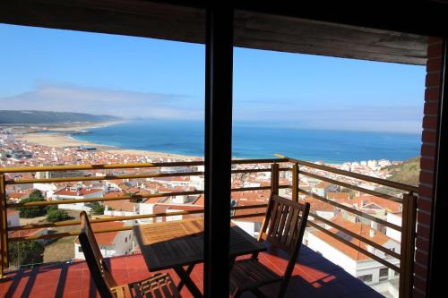 a balcony with a table and chairs and the ocean at NAZARÉ SURF APARTMENT in Nazaré