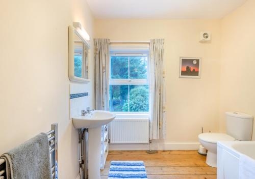 a bathroom with a sink and a toilet and a window at Old Fishermans Cottage - East Runton in West Runton