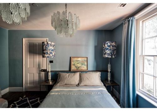 a bedroom with a bed with blue walls and a chandelier at House in Hastings in Hastings