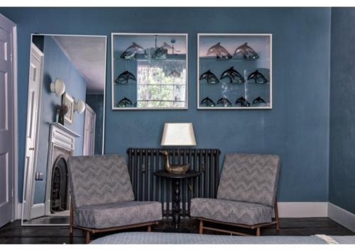 a blue room with two chairs and a table and a window at House in Hastings in Hastings