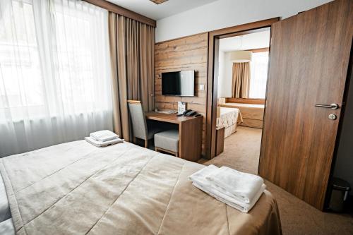 a hotel room with a bed and a desk with a television at Šport Hotel *** Donovaly in Donovaly
