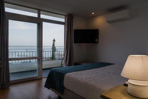 a bedroom with a bed and a large window with a view at Fatima`s House in Funchal
