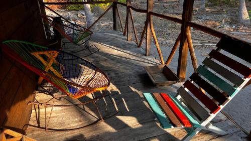 a group of colorful chairs sitting on a porch at Cabañas Casa de Agua in Boca del cielo