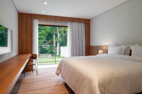 um quarto com uma cama, uma escrivaninha e uma janela em Vert Hotel Penedo em Penedo