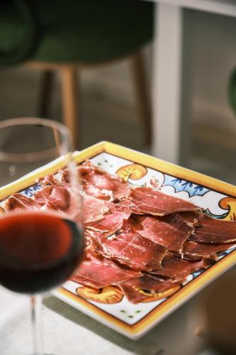 Un plato de carne junto a una copa de vino en Palazzo San Rocco Residenza Gentilizia, en Sperlonga