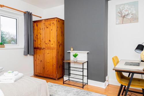 Cozy 1-Bedroom Flat at Abingdon في أوكسفورد: غرفة مع مكتب وخزانة خشبية