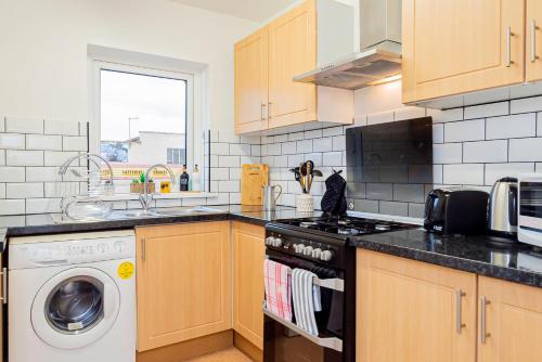 a kitchen with a stove and a washing machine at Cosy Oxford Getaway with Free Parking, Minutes from City Centre in Oxford