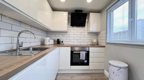 a white kitchen with a sink and a stove at Modern Apartment in Kings Cross in London