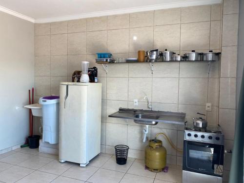 una pequeña cocina con fregadero y nevera. en ZZZCK CASAS PRIVATIVAS 2 DORM AR WIFI VAGAS COZINHa, en Itapema