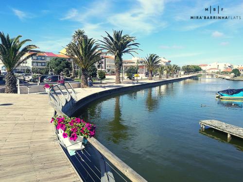 a canal with a boat with flowers on it at Mira'Barrinha Flats in Praia de Mira
