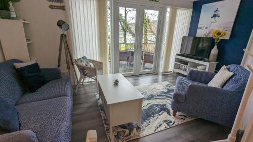 a living room with two blue chairs and a table at 271 Riverside, Glan Gwna Holiday Park in Caeathro