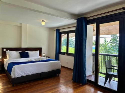 1 dormitorio con 1 cama con cortinas azules y balcón en Villa Salento Boutique Apartments & Spa, en Salento