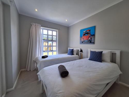 twee bedden in een kamer met een raam bij 4 Periwinkle Place in Kaapstad