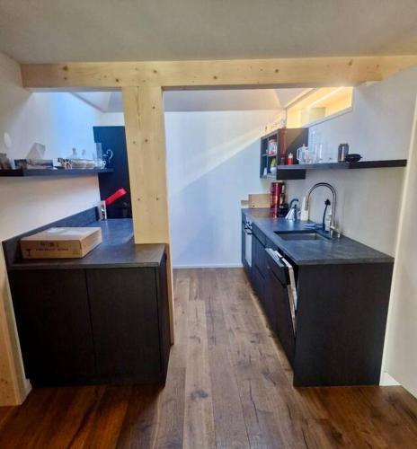 a large kitchen with black counters and a sink at Region de Gstaad - Ultra Modern Apartment- Huge Roof Terrace - Great Views in Zweisimmen