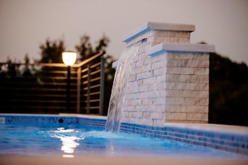 a fountain in the middle of a swimming pool at Etno Villa Mokanji in Danilovgrad