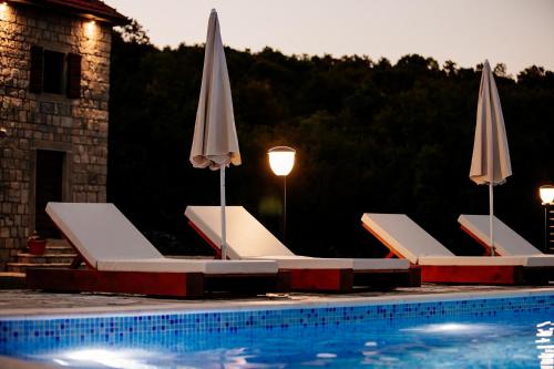 a group of chairs and umbrellas next to a swimming pool at Etno Villa Mokanji in Danilovgrad