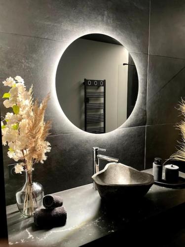 La salle de bains est pourvue d'un lavabo et d'un miroir rond. dans l'établissement Suite Anela, à Saint-Claude