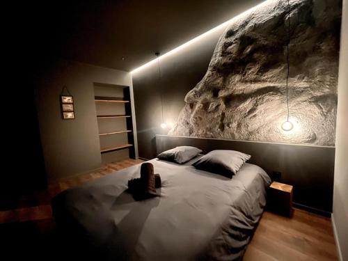 - une chambre avec un grand lit et un mur en pierre dans l'établissement Suite Anela, à Saint-Claude