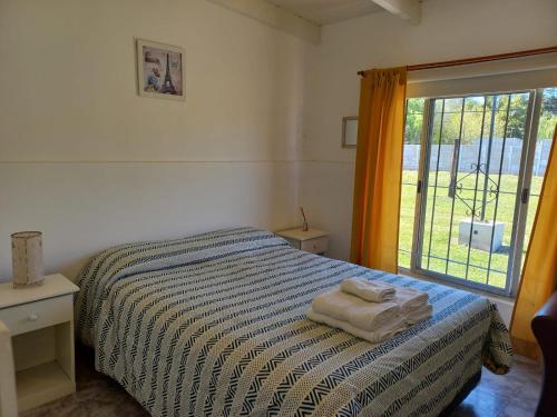 a bedroom with a bed with a striped blanket and a window at Complejo Los Abuelos. in Norberto de la Riestra
