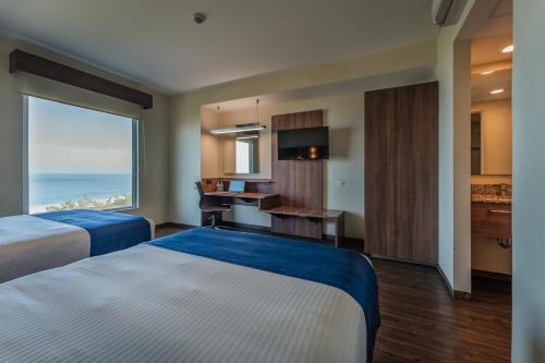 a hotel room with two beds and a large window at La Venta Inn Ciudad del Carmen in Ciudad del Carmen