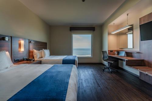 a hotel room with two beds and a desk and a window at La Venta Inn Ciudad del Carmen in Ciudad del Carmen